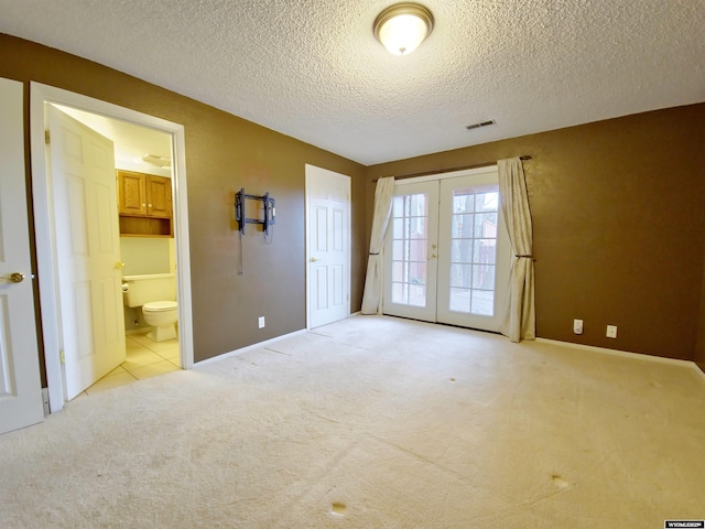 unfurnished bedroom with visible vents, access to exterior, french doors, light carpet, and connected bathroom