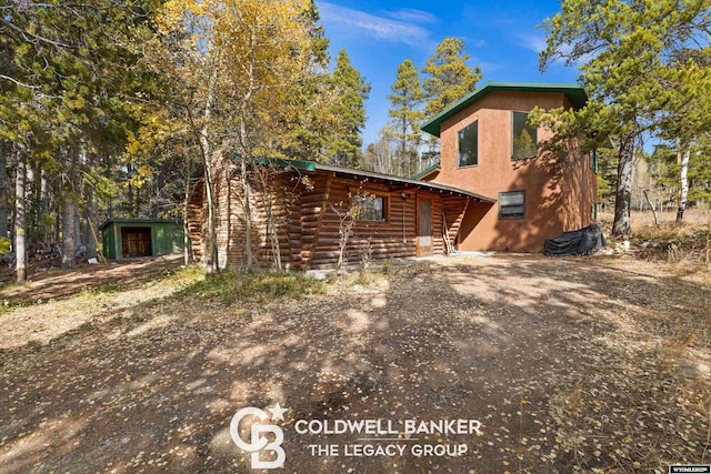 view of front of house with an outbuilding, log siding, and driveway