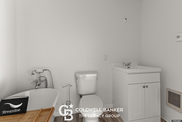 full bathroom featuring visible vents, baseboards, toilet, a soaking tub, and vanity