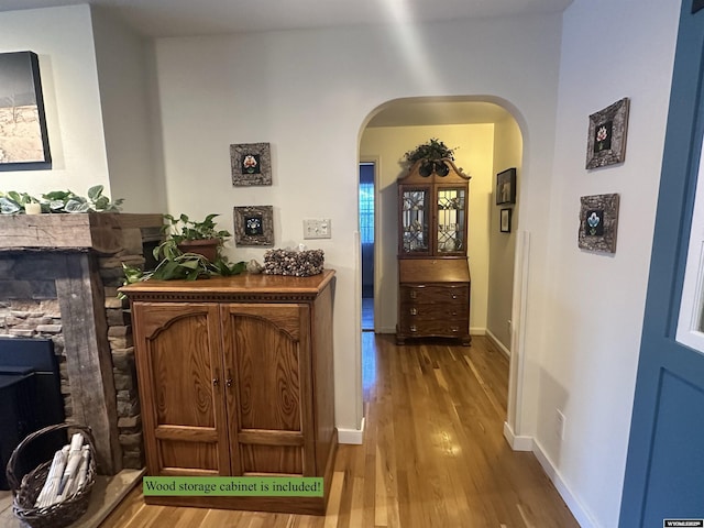 corridor with baseboards, arched walkways, and wood finished floors