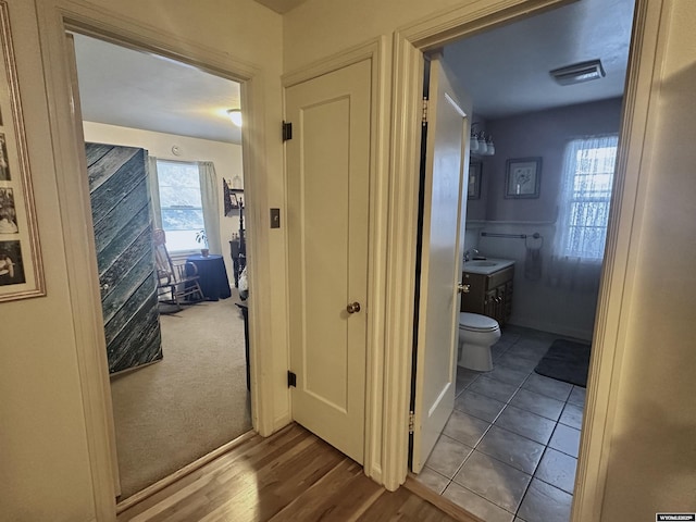 hallway with a sink, visible vents, and wood finished floors