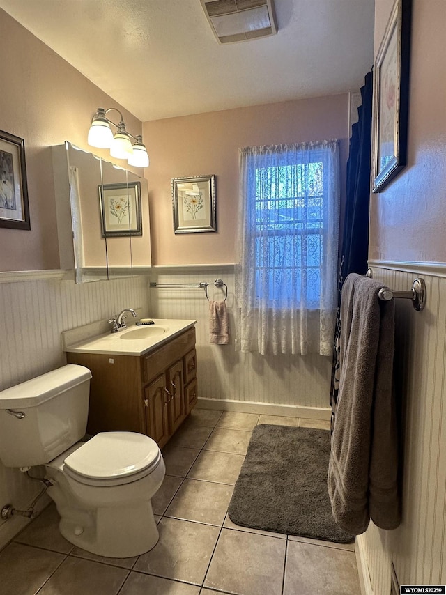 bathroom featuring tile patterned flooring, a wainscoted wall, toilet, and vanity