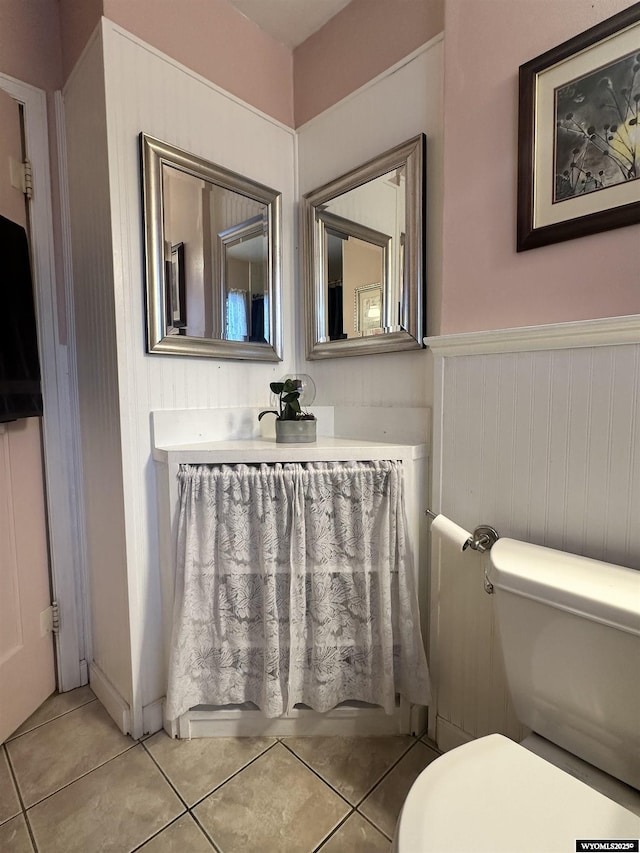 bathroom with tile patterned floors, a wainscoted wall, and toilet