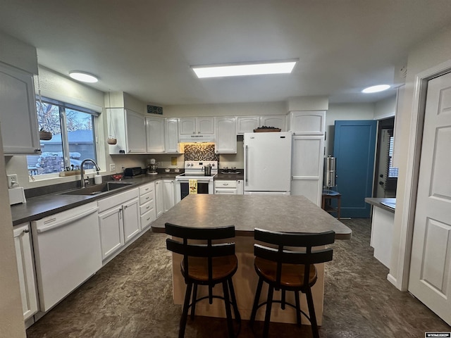 kitchen with a sink, dark countertops, white cabinetry, white appliances, and exhaust hood