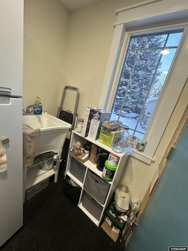 clothes washing area with a textured wall and a sink