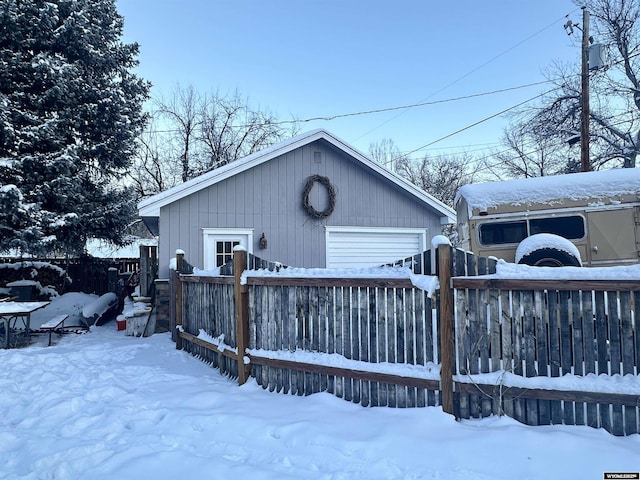 exterior space with a detached garage, an outbuilding, and fence