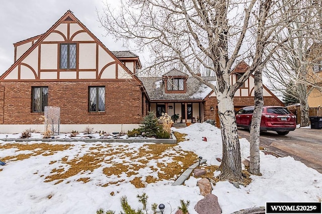 tudor-style house featuring brick siding, stucco siding, and driveway