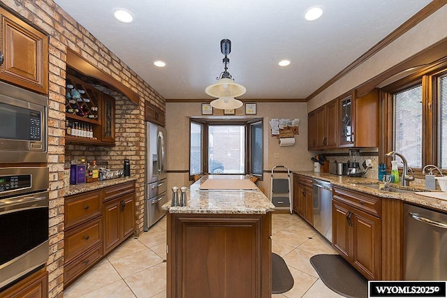 kitchen featuring a sink, stainless steel appliances, glass insert cabinets, crown molding, and a center island