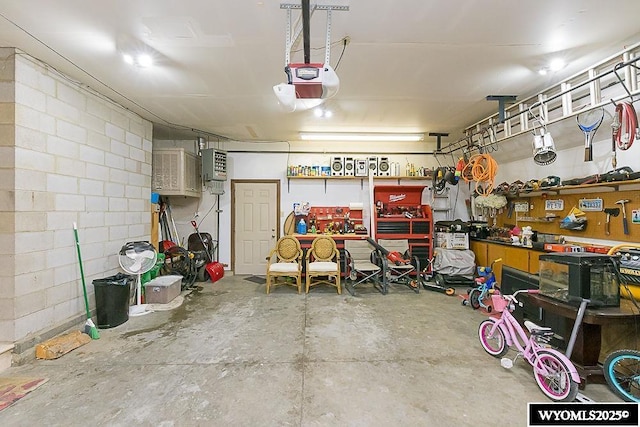 garage with a workshop area, concrete block wall, and a garage door opener