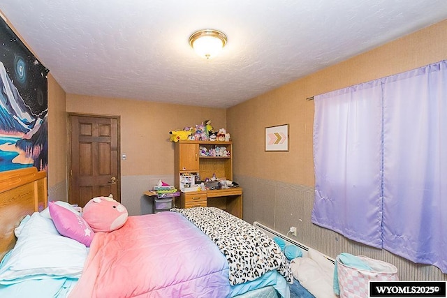 bedroom featuring wainscoting and a textured ceiling