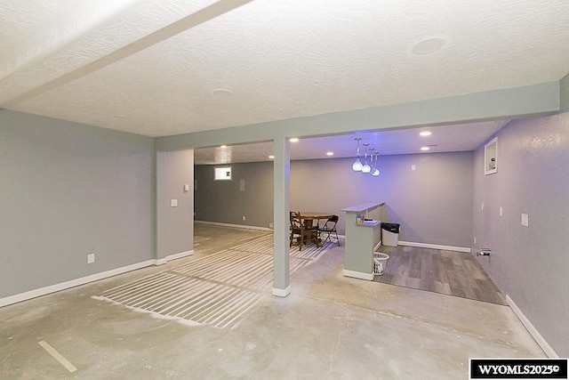 finished below grade area featuring baseboards and a textured ceiling