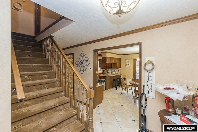 stairs with tile patterned floors, a textured ceiling, and ornamental molding