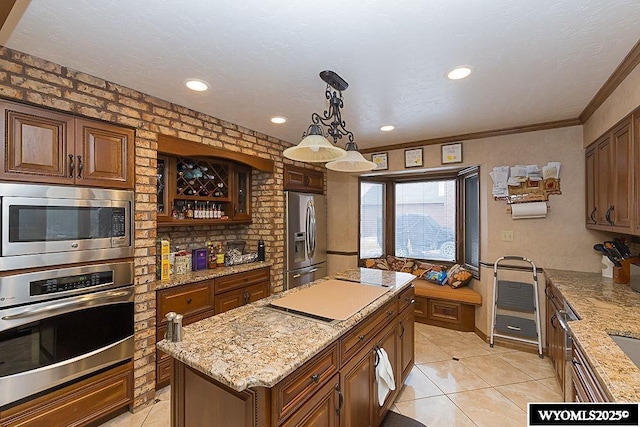 kitchen with a center island, light stone countertops, stainless steel appliances, and ornamental molding