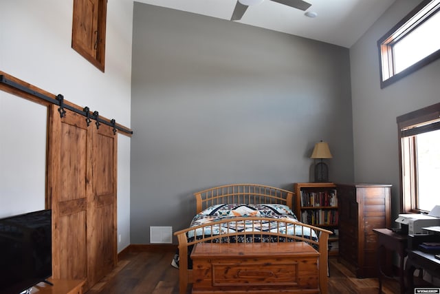 bedroom featuring a high ceiling, multiple windows, wood finished floors, and visible vents