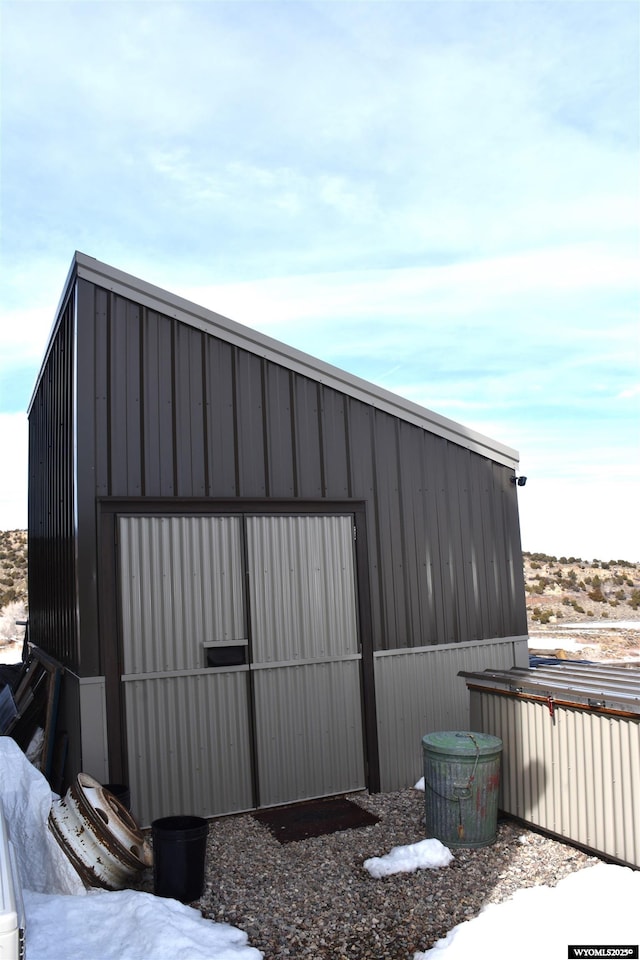 snow covered structure featuring an outdoor structure and a pole building