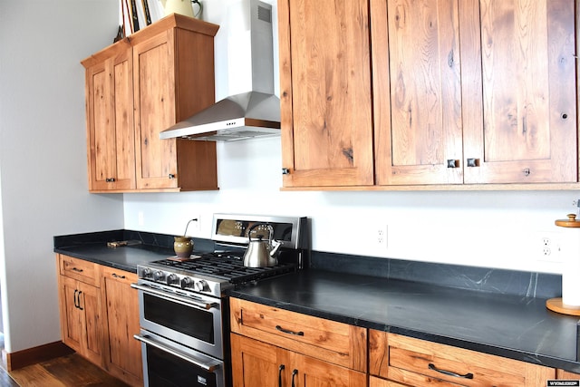 kitchen featuring dark countertops, double oven range, baseboards, and wall chimney range hood