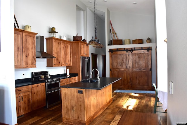 kitchen featuring a sink, dark countertops, appliances with stainless steel finishes, and wall chimney range hood