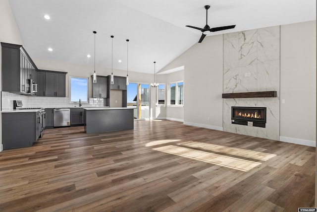 kitchen featuring a high end fireplace, a sink, stainless steel appliances, ceiling fan with notable chandelier, and open floor plan