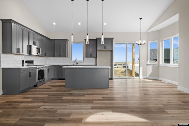 kitchen with gray cabinets, a sink, tasteful backsplash, appliances with stainless steel finishes, and vaulted ceiling