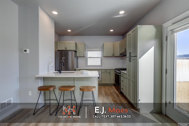 kitchen with tasteful backsplash, visible vents, appliances with stainless steel finishes, a kitchen breakfast bar, and a sink