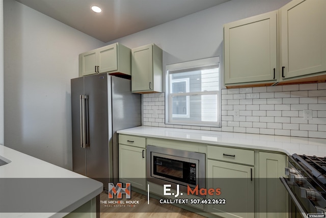 kitchen with backsplash, stainless steel appliances, light countertops, and wood finished floors