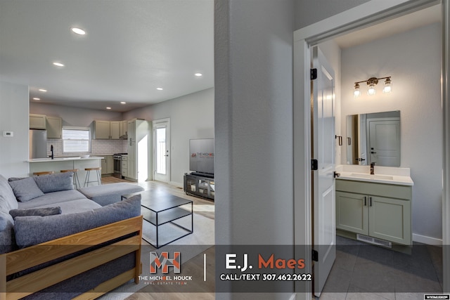 tiled living room featuring visible vents, recessed lighting, baseboards, and a sink