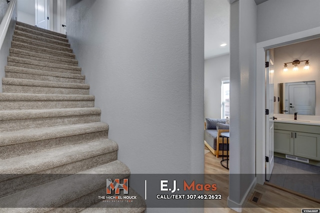 staircase with visible vents, wood finished floors, and a textured wall