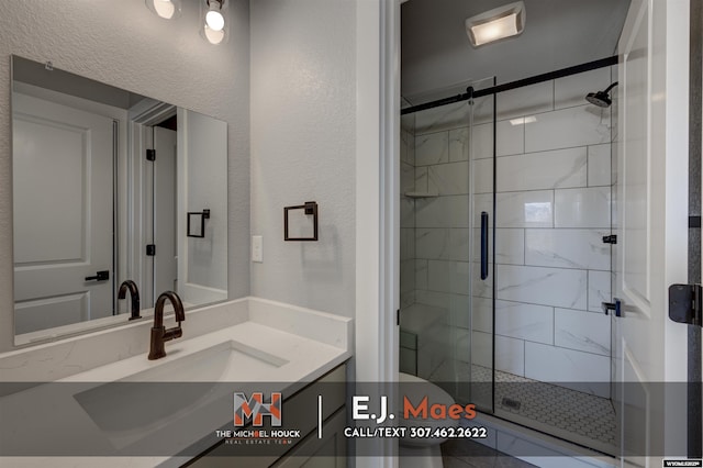 bathroom with a shower stall, vanity, toilet, and a textured wall