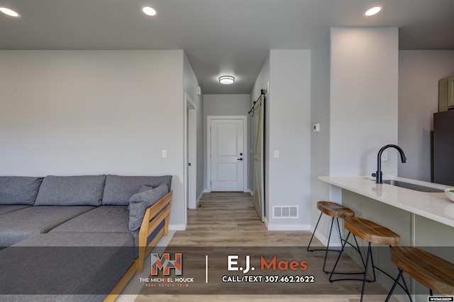 living room featuring recessed lighting, visible vents, a barn door, and light wood-style flooring