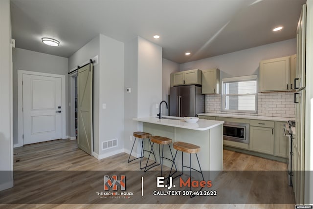 kitchen featuring visible vents, a breakfast bar, high quality appliances, a barn door, and a peninsula