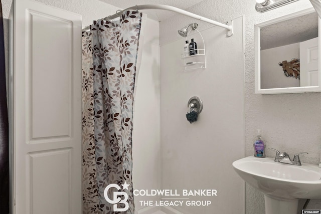 bathroom featuring a sink, a shower with shower curtain, and a textured wall