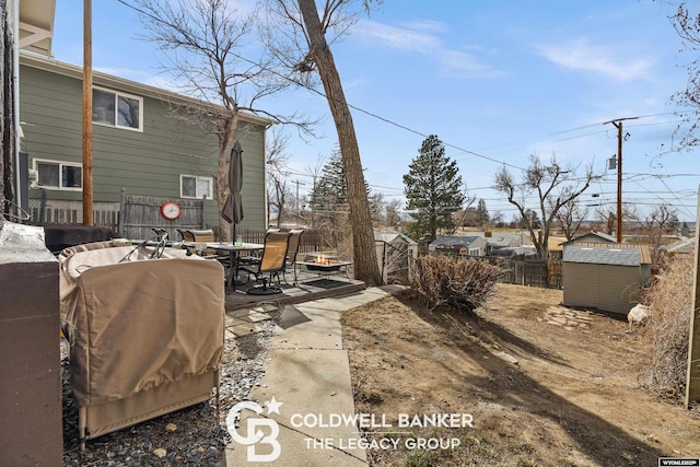 view of yard with a storage unit, an outbuilding, a fenced backyard, outdoor dining area, and a patio area