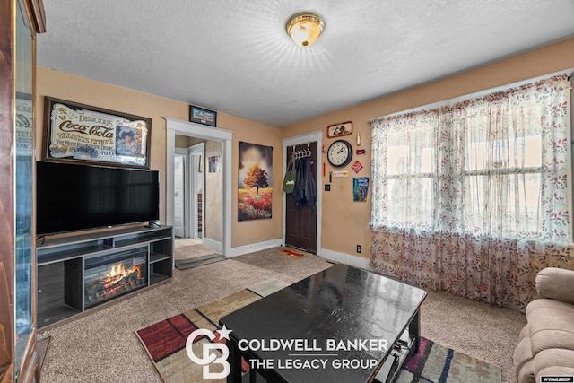 living room featuring baseboards, carpet, a glass covered fireplace, and a textured ceiling