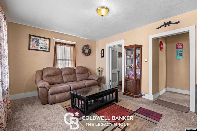 carpeted living room featuring baseboards and a textured ceiling