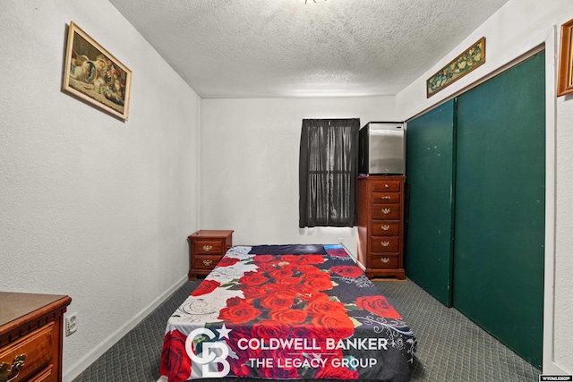 bedroom with baseboards, carpet floors, and a textured ceiling