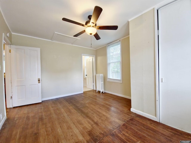 unfurnished bedroom featuring baseboards, a ceiling fan, wood finished floors, and radiator heating unit