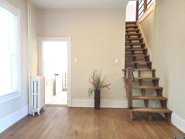 staircase with baseboards, radiator, and hardwood / wood-style floors