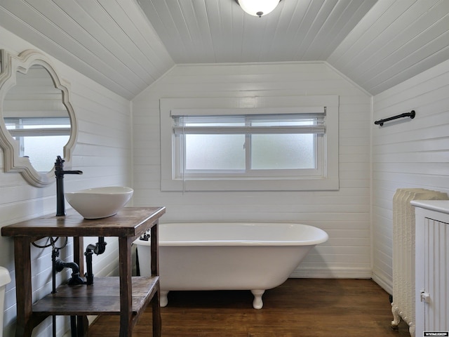 bathroom featuring a soaking tub, wood finished floors, a healthy amount of sunlight, and lofted ceiling