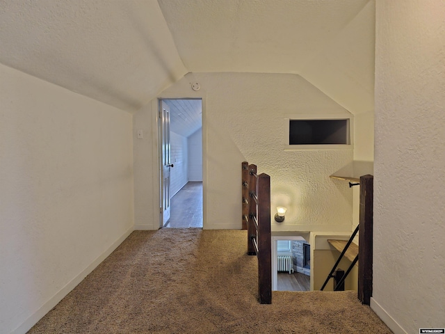 office space featuring baseboards, vaulted ceiling, carpet flooring, a textured wall, and a textured ceiling