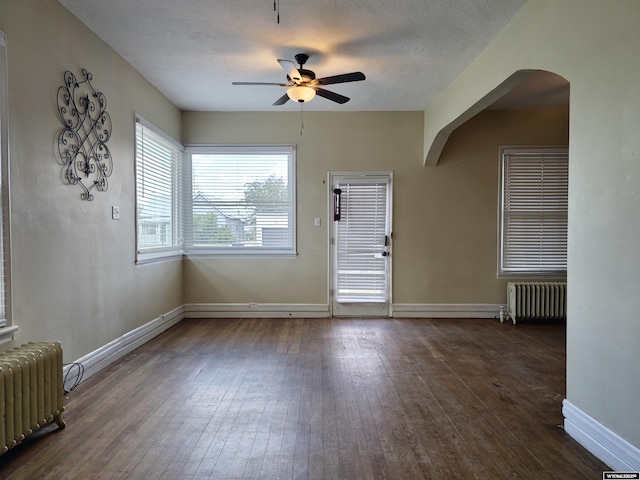 foyer featuring arched walkways, radiator, a ceiling fan, and hardwood / wood-style flooring