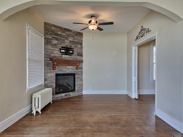 unfurnished living room featuring radiator, baseboards, a ceiling fan, and wood finished floors