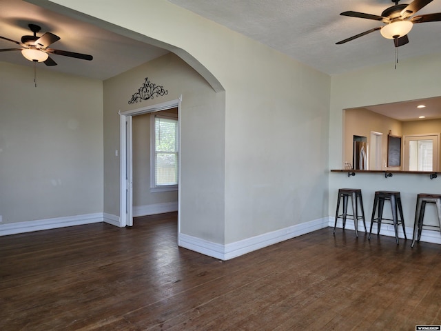 unfurnished room featuring a ceiling fan, baseboards, recessed lighting, arched walkways, and dark wood-style flooring