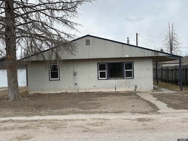 view of side of home with stucco siding and fence