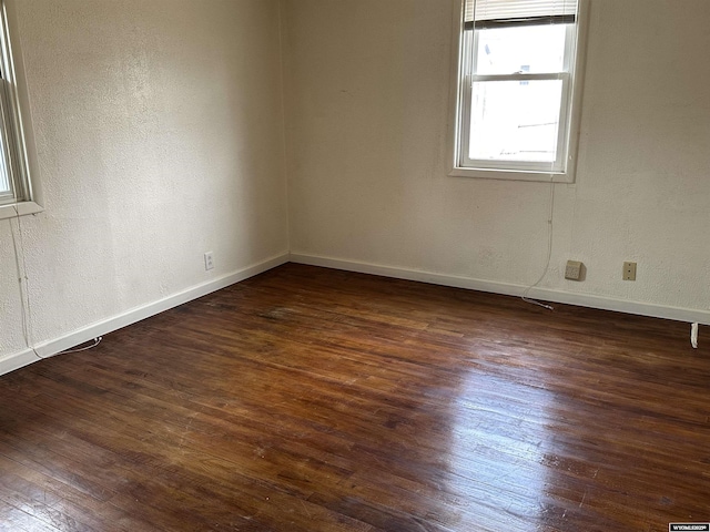 unfurnished room with dark wood-style floors, baseboards, and a textured wall