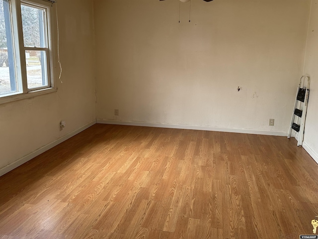 empty room featuring a ceiling fan, baseboards, and light wood finished floors