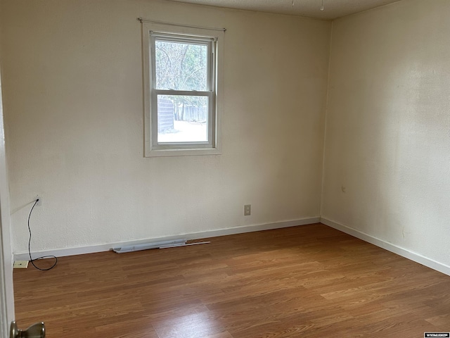 unfurnished room with baseboards and wood finished floors