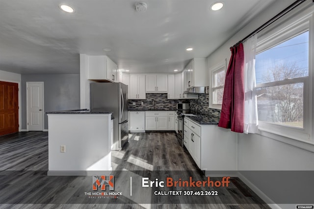 kitchen featuring stainless steel appliances, decorative backsplash, dark wood-type flooring, under cabinet range hood, and white cabinetry