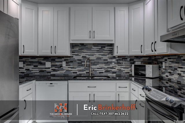 kitchen featuring white appliances, dark stone counters, a sink, white cabinets, and tasteful backsplash