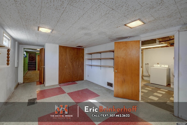 finished basement with tile patterned floors, stairway, visible vents, and washing machine and clothes dryer