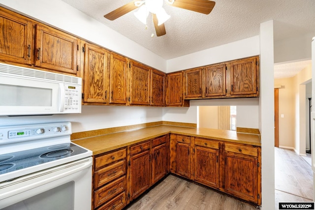 kitchen with brown cabinets, light wood-style flooring, a textured ceiling, white appliances, and ceiling fan